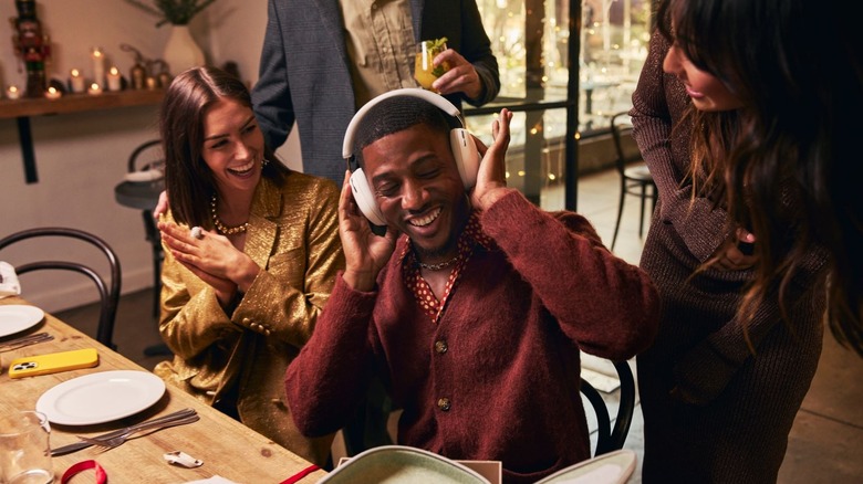 People gather around a man trying on a pair of headphones